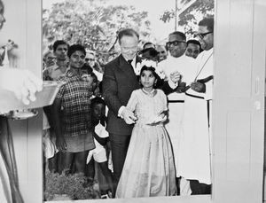 Genindvielsen af Det Kristne Pigegymnasium i Melpattambakkam, Sydindien, 1970. Den danske ambassadør H. A. Biering hjælper en skolepige med saksen