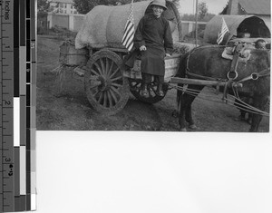 Reverend Alonso M. Escalante, MM seated on a cart before a mission trip, Tunghua, Manchuria, 1934
