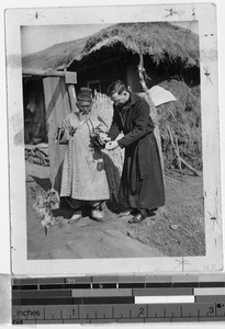 Father Nolan lights elderly man's pipe, Masan, Korea, ca. 1920-1940