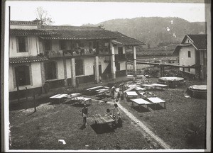 School building in Hoschuwan. Dormitories above, classrooms below. The beds are being washed (this happens once a month). The beds are made of two blocks of wood on which two boards rest, each about 2 metres long and 60 cm. broad. A grass mat is spread out over these boards, and over everything the mosquito net