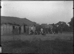 Group of people in front of a building with a thatched roof, Matutwini, Mozambique, ca. 1904