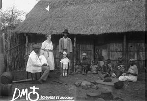 European woman and child and African people in front of a building with a thatched roof, Ricatla, Mozambique, ca. 1924