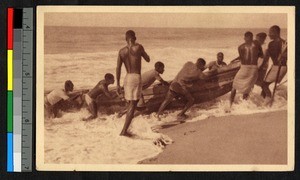 Men pushing a canoe up out of the ocean surf, German East Africa, ca.1920-1940