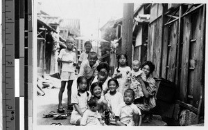 Smiling women and children sitting in an urban street, Japan, ca. 1920/1940