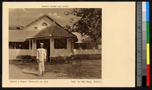 Man standing outside a tile-roofed hospital building, India, ca.1920-1940