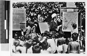 Catholic Sister teaching language to a group of children, Oceania, 1937