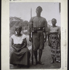 West African soldier in the service of the German Government, with his wife and servant in Buea