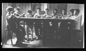 Boys sitting at a table eating, China, ca. 1920-1940