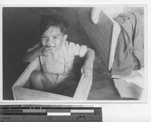 A little boy sitting in a wooden box at Hong Kong, China, 1941