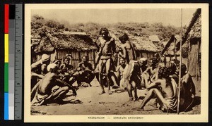 Two men dancing outdoors amid a gathering of others, Madagascar, ca.1920-1940