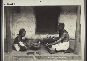 "Indian goldsmith at work. The boy is blowing on the fire."