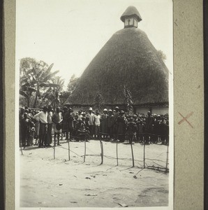 Empfang vor der Kirche i. Bengwi b. Bamendig. Links sitzt der Häuptling, rechts der Evangelist Asili. Hier wurden innerhalb von 8 Jahren 3 Kirchen gebaut, bald ist auch diese zu klein. (1928)
