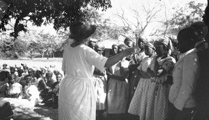 European woman conducting a choir of African children, southern Africa