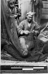 Japanese man mending a fishing net, Japan, August 1932