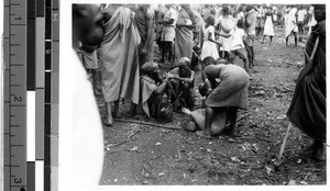 Four people in a circle among a larger group of people, Africa, ca. 1920-1940