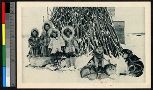 People and sled dogs standing before a large pile of sticks, Alaska, ca.1920-1940