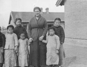 Blind home Blind School in Mukden. Helen Madsen with some of the smallest blind girls and 2 tea