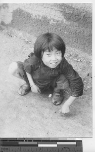 A girl playing with rocks at Fushun, China, 1940