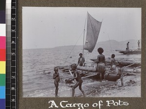 Group with canoe carrying load of pots, Delena, Papua New Guinea, ca. 1905-1915