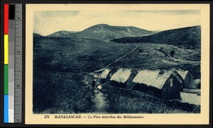 Missionary father distributing medicines outside a gathering of thatch-roofed buildings, Madagascar, ca.1920-1940