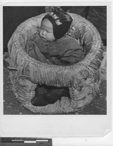 A baby in a basket at Chuangxian, China, 1946