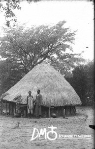 African couple in front of a hut, Mozambique, ca. 1896-1911