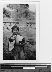 An orphan girl holds an orphan newborn at Luoding, China