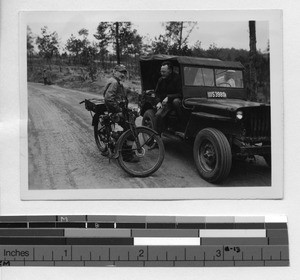 Fr. Arthur Cunneen riding a bicycle and Fr. Tennien in jeep at Wuzhou, China, 1948