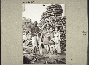 Beggar-children saw wood in front of the doctor's house in Kayin, 1920