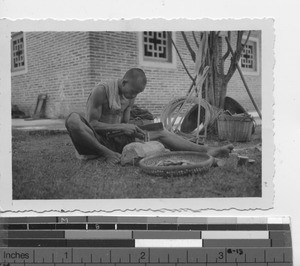 A man making repairs on rice grinder at Luojing, China, 1937