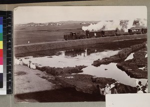 Steam train passing by rice field, Madagascar, ca. 1910