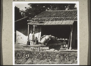 Primitive Teehütte, im Vordergrund ein Schubkarren. (auf den Schubkarren sind Reissäcke geladen, mit einem solchen Karren können sie 3-5 Zentner fortschaffen)