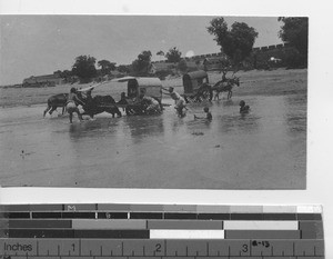Travelers with carts crossing a river at Chefoo, China, 1917