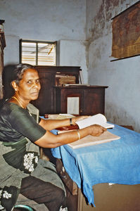 23.- Tamil Nadu, Indien, 1988-89. "Med 80 elever i klassen" - En dansk lærer i Arcot skoleprojekt fortæller: Edith sidder på sit kontor, som samtidig er lærerværelse for 14 lærere. Som vi kan se, er det ikke særlig stort, men kan dog lade sig gøre. Her kom jeg hver torsdag og fik først en hyggelig snak med hende, inden vi havde engelsktime med lærerne på skolen. Vi prøvede at lege, lave dramatik, synge og lave små dialoger, som vi senere brugte i engelsk undervisning af eleverne