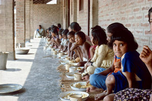 Diasserie for børn: "En dag på Saraswatipur Kostskole"- Nr. 20. Vi spiser udenfor vores værelser. Vi lægger stråmåtter på gulvet, finder krus og tallerken frem, og så kommer risen