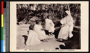 Indigenous nun sitting outdoors and instructing children in the catechism, Madagascar, ca.1920-1940