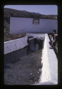 girl and boy beside drainage culvert