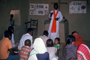 Diasserie "BLC - ung kirke i Bangladesh" - Gudstjeneste i BLC, Nr. 04 - BLC betyder "Bangladesh Lutheran Church" - altså Bangladesh Lutherske Kirke. Præsterne i BLC bærer præstekjole under gudstjenesten. Her er præstens stola gylden, men han bruger også en lilla eller grøn stola, så det passer til kirkeåret