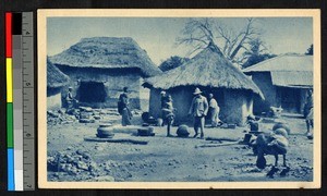 Missionary standing amid thatch-roofed huts, German East Africa, ca.1920-1940