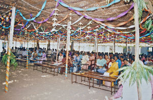 43.- Tamil Nadu, Indien, 1988-89. "Med 80 elever i klassen" - En dansk lærer i Arcot skoleprojekt fortæller: Vi havde et stort kursus i januar 1989, hvor alle lærere fra kirkens skoler kom, og de sidder her fint under pandaens skygge. Det var nemlig sådan, at skoleprojektet havde inviteret alle lærere fra ALCs skoler – også dem, der endnu ikke var med i projektet. De lærere, som havde været med i projektet fra starten, stod som arrangører af kurset. De ville gerne give gode ideer og deres begejstring videre til deres kolleger