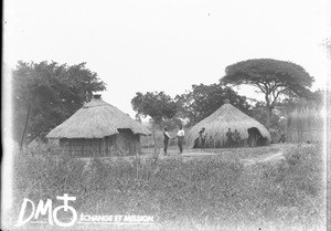 African people standing in front of huts, Makulane, Mozambique, ca. 1896-1911