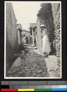 Abbie G. Sanderson standing in a village street, Shantou,Guangdong, China, 1919