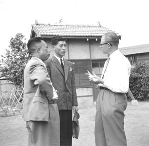 Den Lutherske Kirkesynode i Kaohsiung, 18.-19. november 1956. Imellem møderne går drøftelserne videre. Her er to repræsentanter fra Hsinchu i samtale med missionær, pastor Anders B. Hanson, LCA (th). Den ene er fhv. mandarin på hovedlandet, men er blevet kristen her og bruger sin dygtighed i kirkens tjeneste. (Anvendt i: Dansk Missionsblad nr 9/1957)