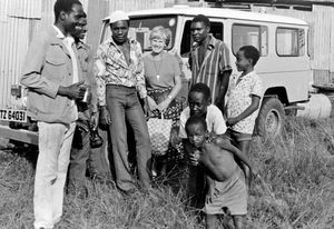 Seniorvolontør Grethe Lund (f. Damgaard), og lokale medarbejdere fra Nyakahanga Hospital, 1986. Hospitalets ambulance ses i baggrunden. (Missionær Grethe Damgaard var udsendt som lærer ved Kibetaskolen for missionærbørn i Bukoba, 1953-68)