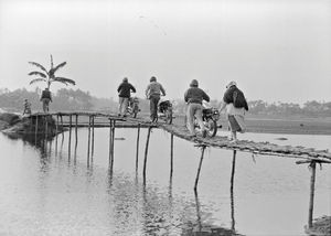 Crossing a rickety bridge for visiting the Supoth project in Bangladesh. Adult Saving Groups, J