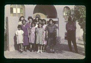 Women, girls and man in front of building