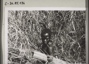 An african woman walking through grass on the way to the market