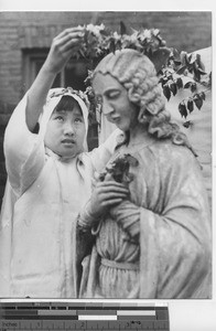 A girl crowns a statue at Fushun, China, 1938