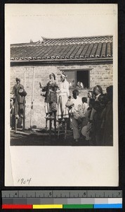 Performers standing on stilts outside a building, Jiangsu, China, ca.1905