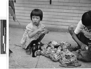 Japanese girl crouching on a sidewalk, Japan, ca. 1949